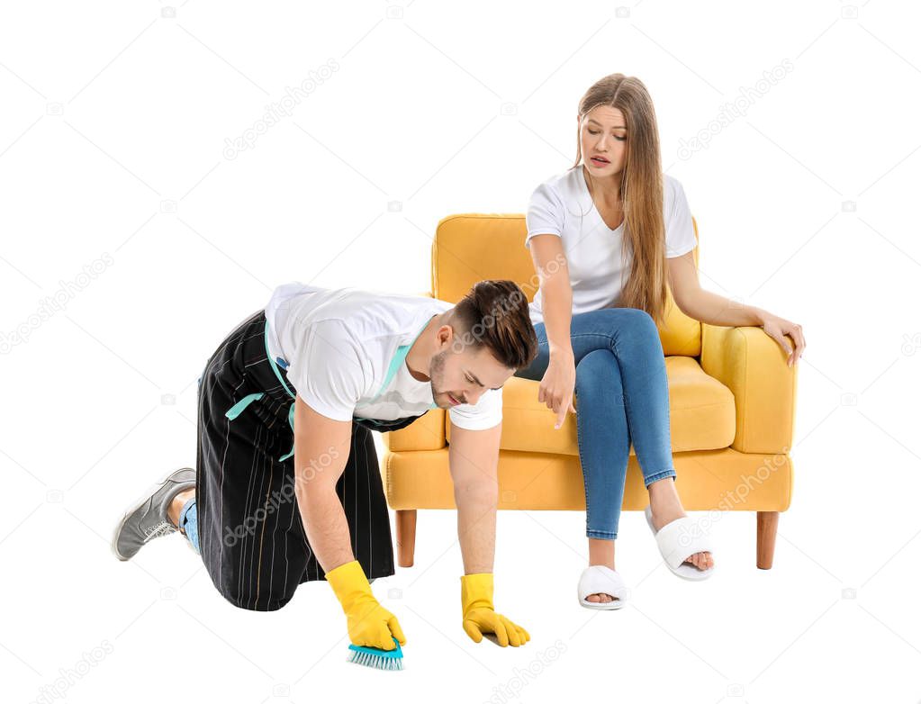 Young husband doing chores while his lazy wife sitting in armchair against white background