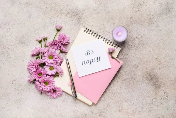 Композиція з красивими квітами, блокнотами, свічкою та карткою на сірому фоні — стокове фото