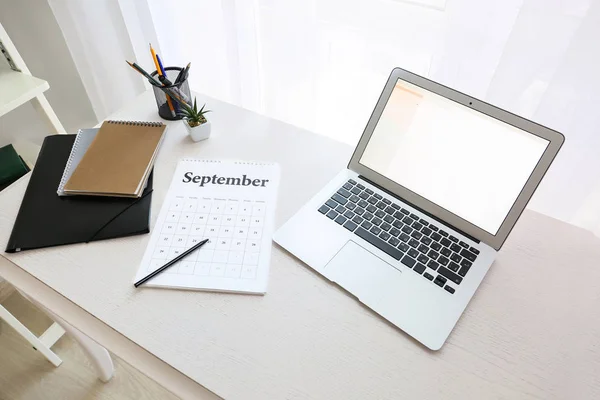 Flip calendar with laptop on table in room — Stock Photo, Image