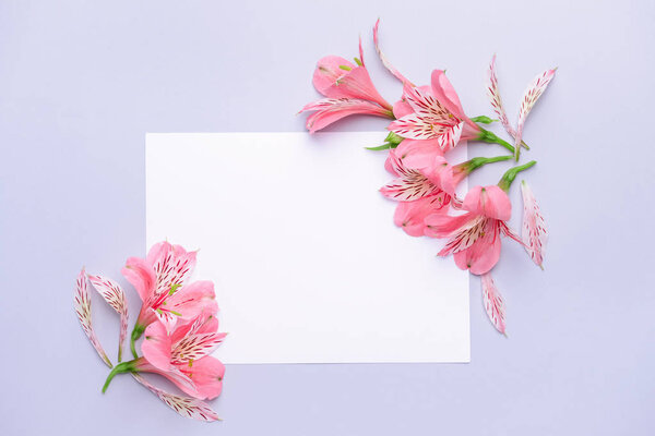 Beautiful fresh flowers and blank card on light background