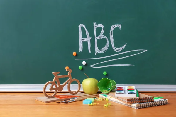 Set of school supplies on table in classroom — Stock Photo, Image