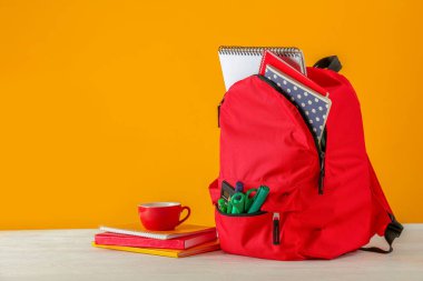 Renk arka plana karşı masada okul malzemeleri ile sırt çantası