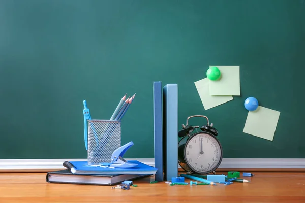 Set di forniture scolastiche e orologio sul tavolo in aula — Foto Stock