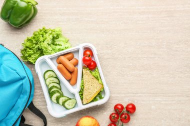 Ahşap arka planda lezzetli yemek ve okul çantası ile öğle yemeği kutusu