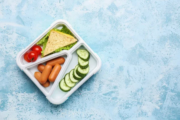 Scatola da pranzo con cibo gustoso su sfondo a colori — Foto Stock