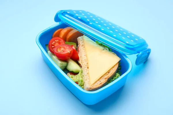 Scatola da pranzo con cibo gustoso su sfondo a colori — Foto Stock