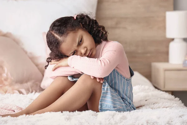 Θλιμμένο μικρό Αφρο-Αμερικάνικο κορίτσι κάθεται στο κρεβάτι — Φωτογραφία Αρχείου