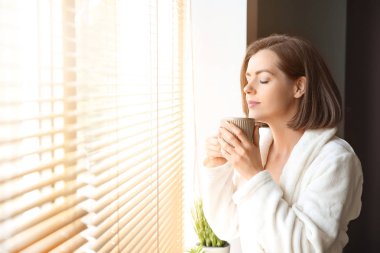 Güzel genç kadın sabah pencere yakınında kahve içme