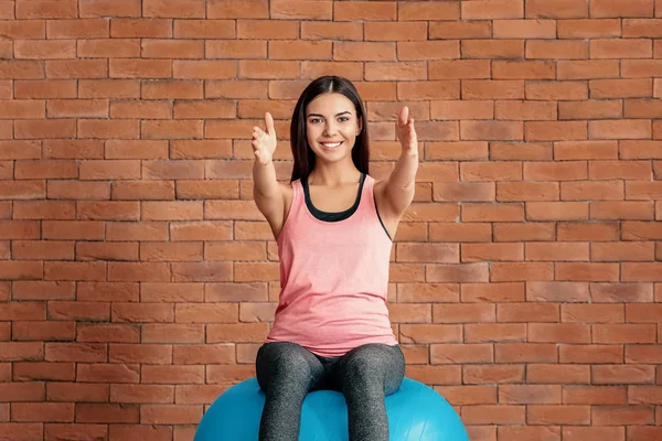 Jonge sportieve vrouw met fitball doen oefeningen in de buurt van bakstenen muur — Stockfoto