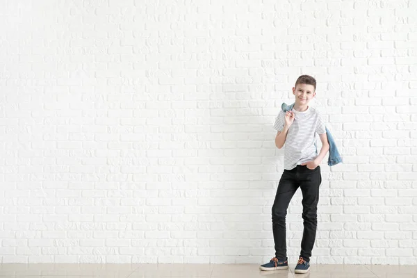 Стильний хлопчик в джинсовому одязі біля білої цегляної стіни — стокове фото
