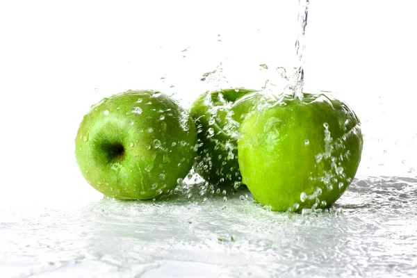 Verter de água em maçãs contra fundo branco — Fotografia de Stock