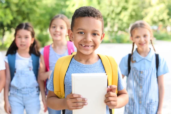 Cute little African-American schoolboy with friends outdoors — Stock Photo, Image