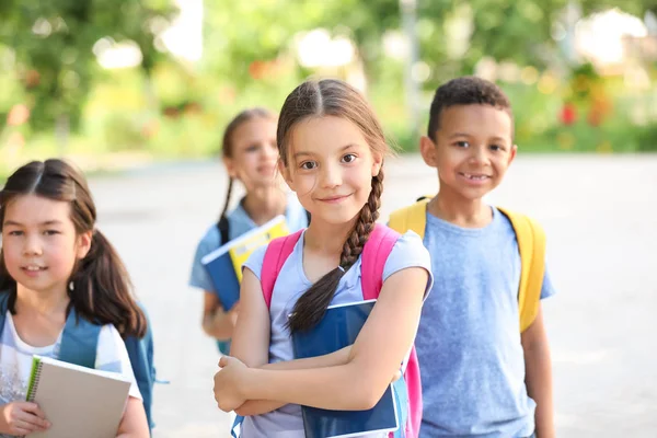 Petite écolière mignonne avec des camarades de classe en plein air — Photo