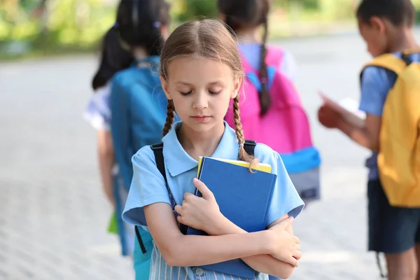 Triste menina e seus colegas de classe ao ar livre — Fotografia de Stock