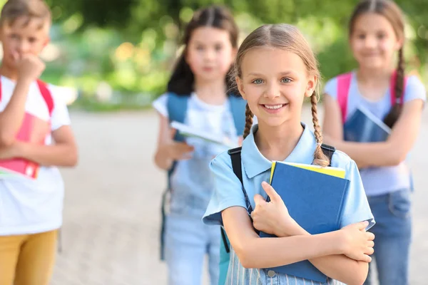 Cute little schoolgirl with friends outdoors — Stock Photo, Image