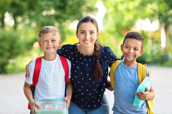 Porträtt av mamma och hennes små söner med skollunch utomhus — Stockfoto