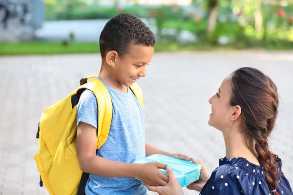 Mãe dando almoço escolar para seu pequeno filho ao ar livre — Fotografia de Stock