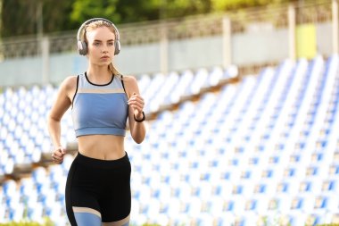 Sportif genç kadın stadyumda koşuyor