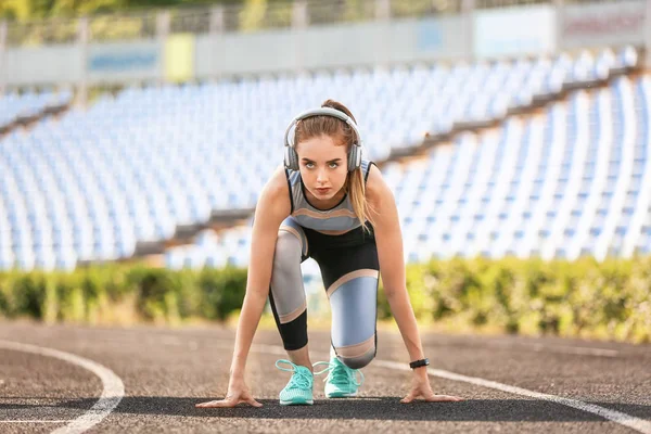 Sporty young woman in crouch start position at the stadium — Stock Photo, Image
