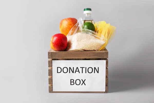 Caja con alimentos de donación sobre fondo gris — Foto de Stock