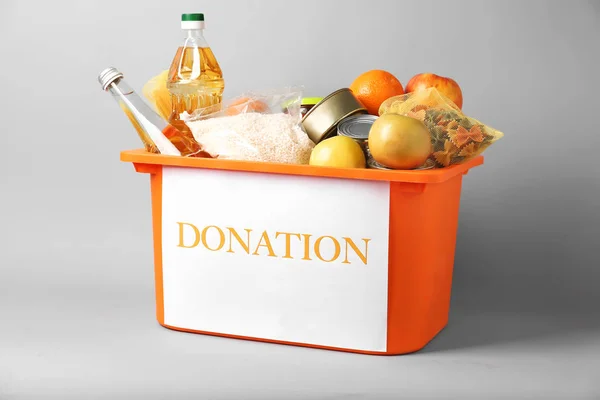 Box with donation food on grey background