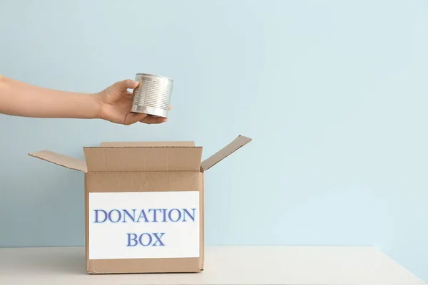 Volontär sätta konserverad mat i donation box på bordet — Stockfoto