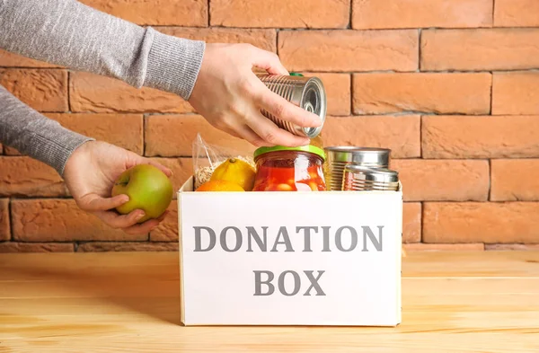 Voluntario poniendo comida en la caja de donaciones en la mesa — Foto de Stock