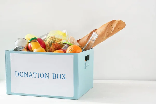 Box with donation food on white background