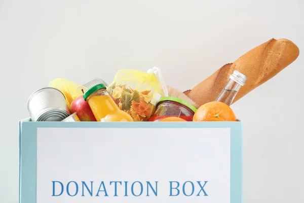 Caja con donación de alimentos sobre fondo claro — Foto de Stock