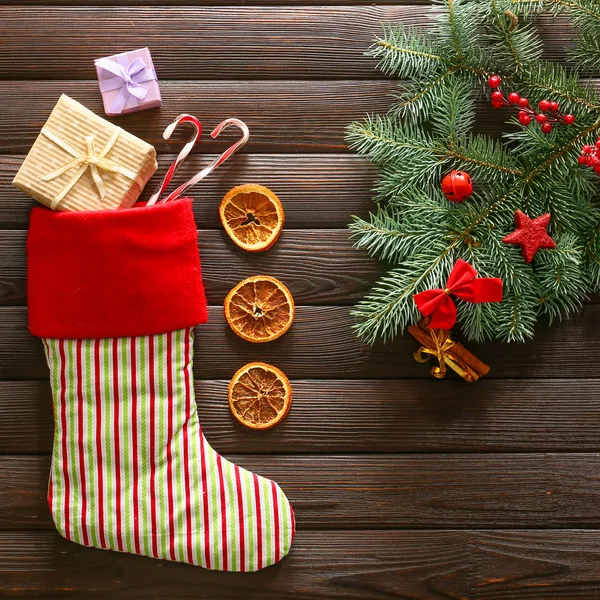 Χριστουγεννιάτικο δέντρο κλαδί, διακόσμηση και κάλτσα με δώρα σε ξύλινο φόντο — Φωτογραφία Αρχείου