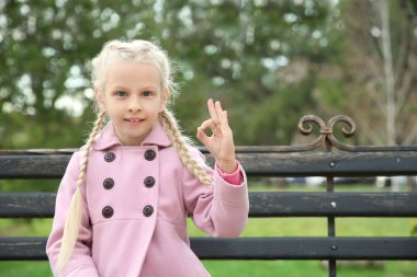 Küçük sağır dilsiz kız açık havada işaret dili kullanarak