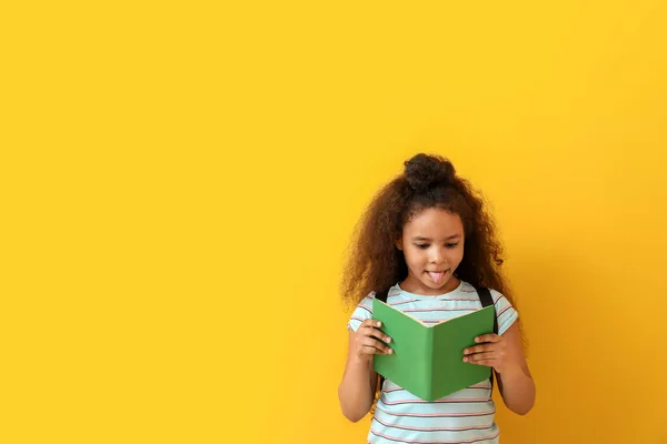 African-American girl reading book on color background — Stock Photo, Image