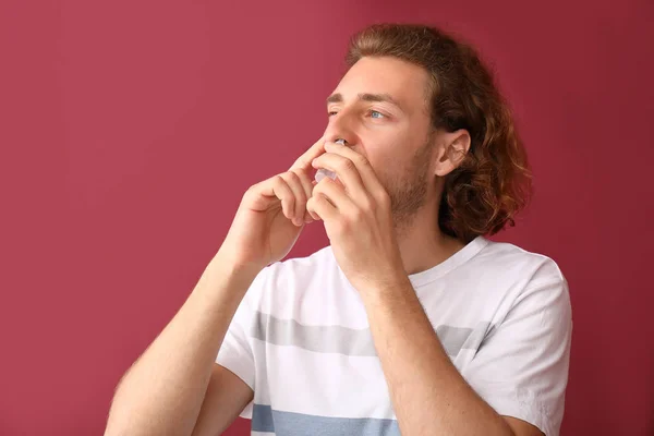 Young man with nasal drops on color background — Stock Photo, Image