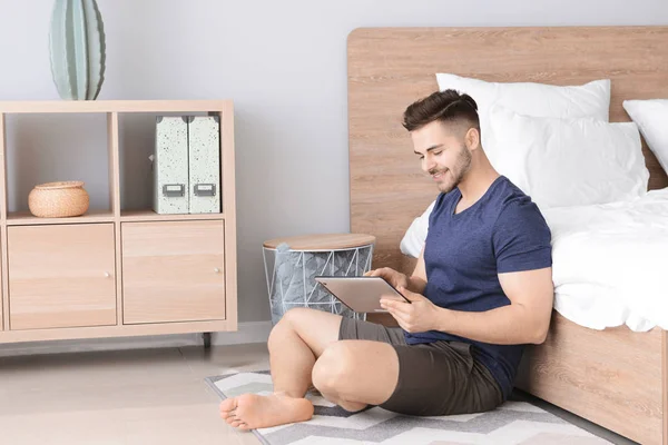 Homem bonito com computador tablet descansando no quarto — Fotografia de Stock