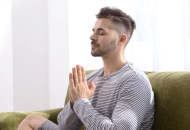 Yakışıklı adam evde kanepeüzerinde meditasyon
