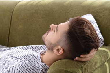 Evdeki kanepede uyuyan yakışıklı adam.