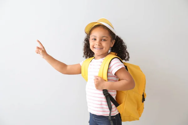 Portrait of stylish little African-American girl pointing at something on light background — Stock Photo, Image