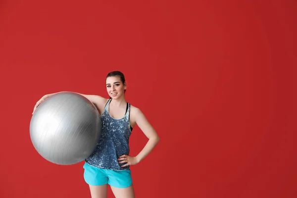 Giovane donna sportiva con fitball su sfondo di colore — Foto Stock
