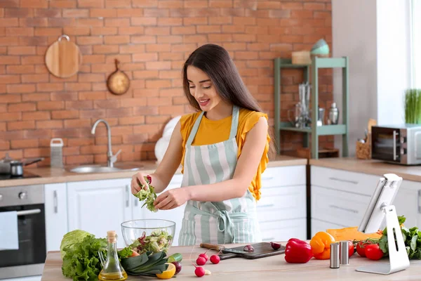 Beautiful woman preparing tasty vegetable salad in kitchen at home — Stock Photo, Image