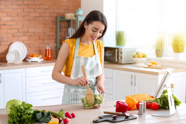 Hermosa mujer preparando sabrosa ensalada de verduras en la cocina en casa —  Fotos de Stock