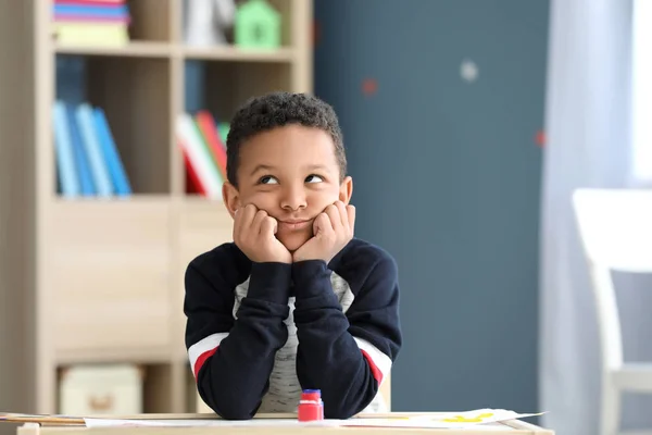 Bored African-American boy sitting at table in room — Stock Photo, Image