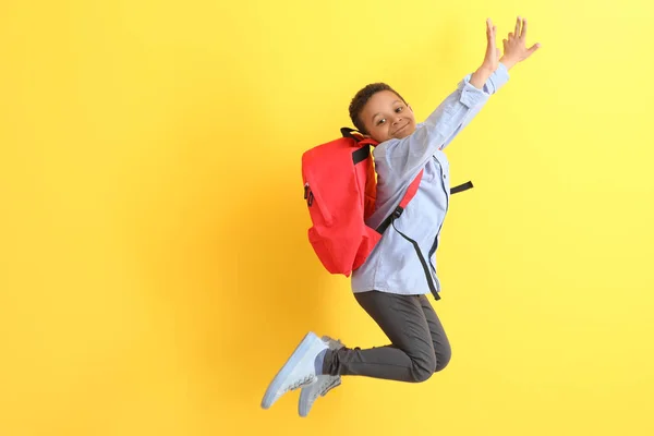 Jumping African-American schoolboy on color background — Stock Photo, Image