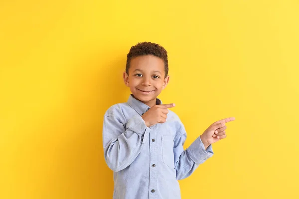 Śliczne African-American chłopiec wskazując na coś na tle koloru — Zdjęcie stockowe