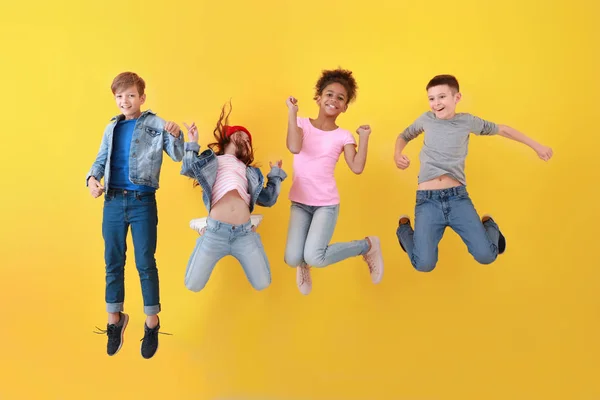 Enfants sautant en jeans près du mur de couleur — Photo