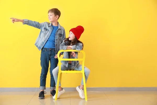 Enfants élégants en jeans vêtements près du mur de couleur — Photo