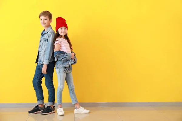 Стильні діти в джинсовому одязі біля кольорової стіни — стокове фото