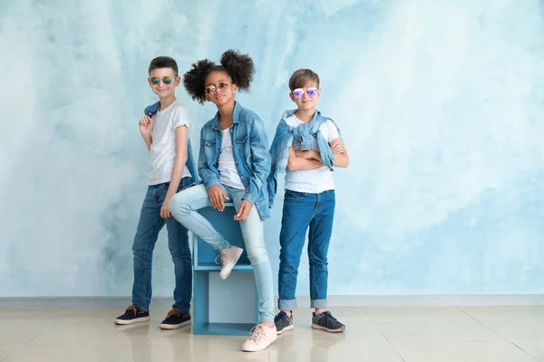 Bambini alla moda in jeans vestiti vicino alla parete di colore — Foto Stock