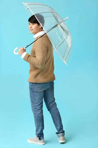 Handsome Asian man with umbrella on color background — Stock Photo, Image