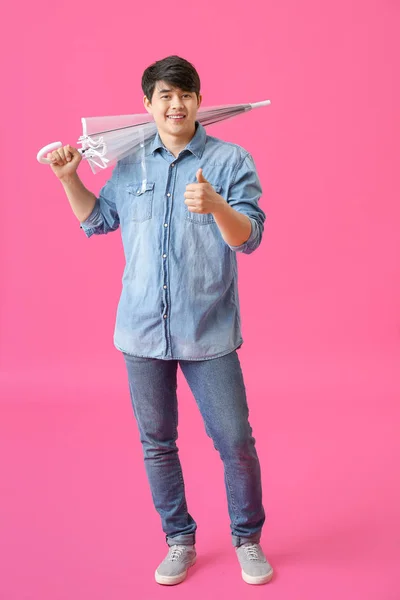 Renk arka planda thumb-up gösteren şemsiye ile Yakışıklı Asyalı adam — Stok fotoğraf