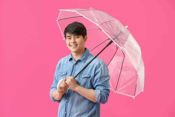 Handsome Asian man with umbrella on color background — Stock Photo, Image